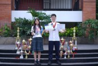 Ava Mikayla Emmanoelle Kasih (14) dan Sean Levi Danuseputra (15) tampak berfoto sambil mengenakan medali, dikelilingi oleh berbagai piala, serta memegang sertifikat penghargaan dari kompetisi yang pernah mereka juarai. (Dok. Sekolah Pelita Harapan LV)